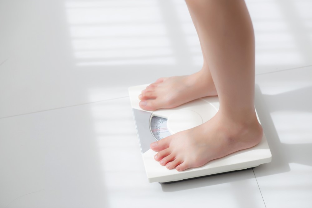 A person stands on a traditional body scale