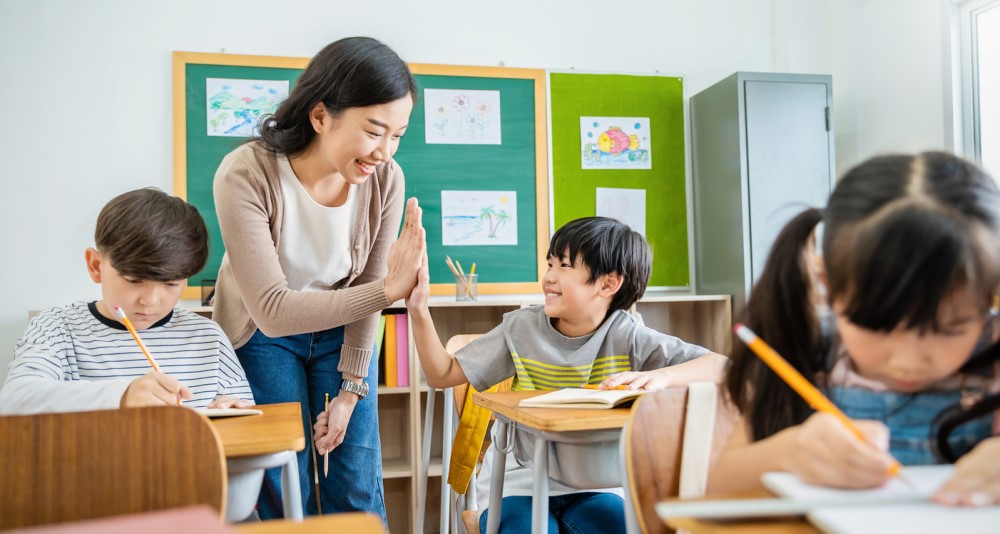 A child interacts with his teacher happily at the classroom.